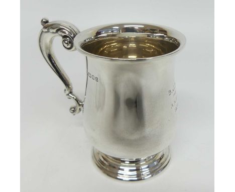 A George V silver tankard, of bell shape with flaring rim, S-scroll handle with scrolling thumbpiece and stepped circular bas