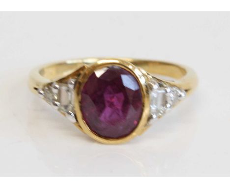 An 18ct yellow gold ruby and diamond dress ring comprising an oval ruby in a bezel setting with a baguette and single cut dia