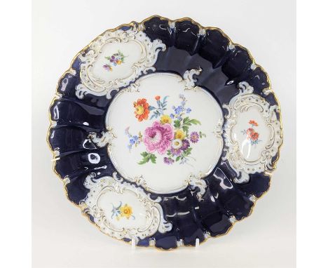 A Meissen porcelain cabinet plate, enamel decorated with flowers within a blue and gilt border, crossed swords and paper labe