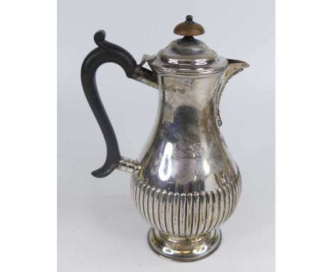 A Victorian silver hot water jug, of half-reeded baluster form, engraved with a lion rampant crest to one side, having a dome