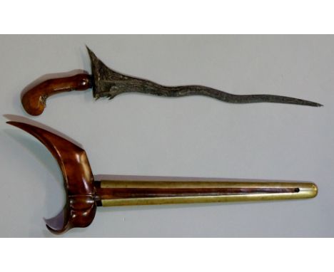 A Sarawak dagger with iron blade, finely carved handle and guard, the scabbard brass cased, 48cm long overall (faults)