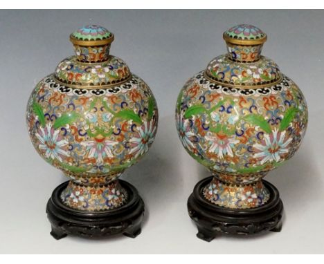 A pair of cloisonne enamel jars, the bodies with scroll and flower design, gilded rims, blue and purple flower to top of knop