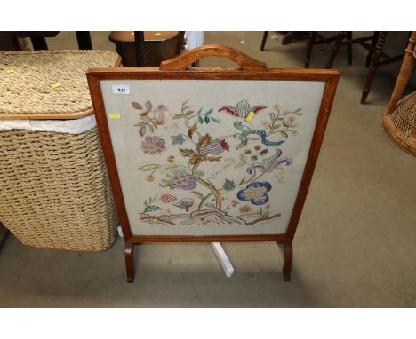 An oak framed embroidered fire screen