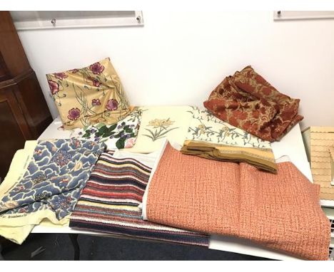 A collection of textiles including tablecloths and curtain material, some with floral design such as irises and brambles, ano