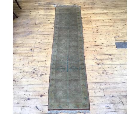 A handwoven wool runner of Caucasian design, the pale brown field with central pole issuing hooked designs within pistachio g