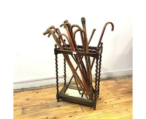 A 1930s oak stick stand, the rectangular top with six divisions and turned finials, raised on barley turned supports, the bas