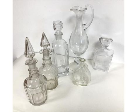 A glass claret jug of ewer form (h.35cm x 12cm x 11cm), a glass flask, dated 1842-1967, two decanters of bell form, one decan