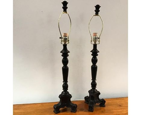 A pair of ebonised table lamps of baluster form, on a tripod base, with matching finial to top of shade holder (h.74cm to top