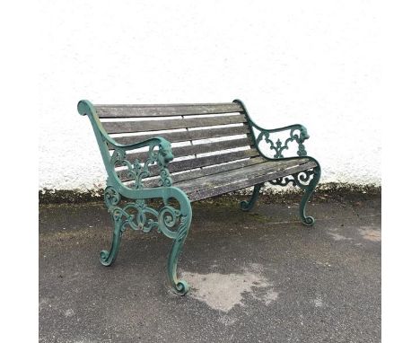 A modern green painted cast iron bench, the pierced ends incorporating lion mask terminals, raised on scroll legs, supporting