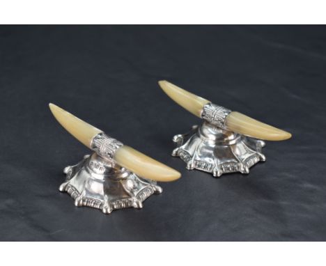 A pair of Edwardian silver and Mother-of-Pearl knife rests, the shaped Mother-of-Pearl platforms raised on spiralled and moul