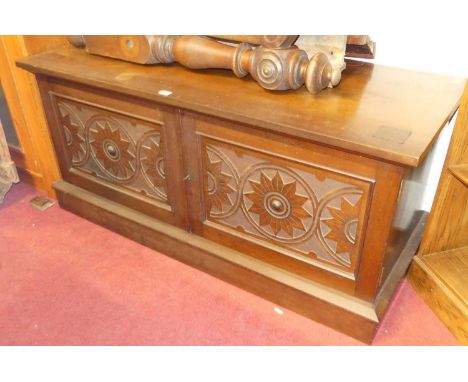 A walnut low double door side cupboard having stylised flower head blind carved detail, width 137cm