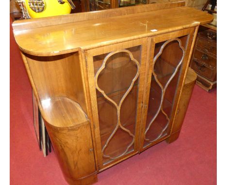 An Art Deco figured walnut round cornered double door glazed cabinet display, the open side upper compartments over conformin