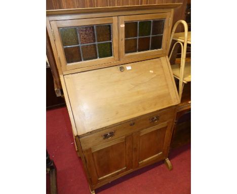 An early 20th century beech squat bureau cabinet, having twin lead glazed upper doors, width 86cm