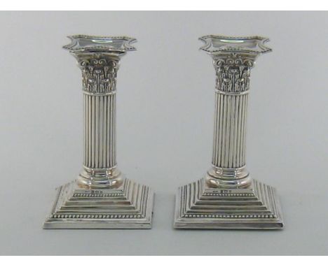 A pair of Edwardian silver Corinthian column dwarf candlesticks by Henry Matthews, Birmingham, 1901, with bead borders and st