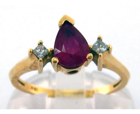 A ruby and diamond ring, the central pear cut ruby 7 x 5mm between two table cut diamonds, the shank stamped '18k', finger si
