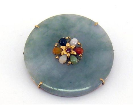 A jade brooch, the disc shaped jade set to the centre with a rosette of multi-coloured jades, a ruby to the centre, mounted i