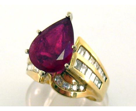 A ruby and diamond ring, the large pear cut stone 13.5 x 9.9mm, to wide baguette and brilliant cut channel set shoulders, the