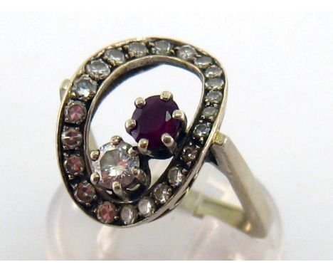 A diamond and ruby ring, the open work oval bezel pave set with brilliants, claw set within with obliquely set round cut ruby