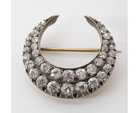 A DIAMOND CRESCENT MOON BROOCH set with estimated approx 2.83cts of old cut diamonds set in yellow and white metal galleried 