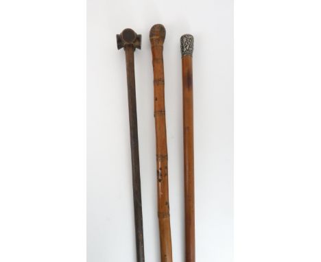 AN AFRICAN WALKING STICK the grip carved in four sections, 82cm long, a malacca cane with white metal embossed handle, 90cm l