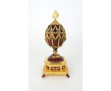 A FRANKLIN MINT MUSICAL GOLD PLATED SILVER FABERGE IMPERIAL EAGLE EGG with red guilloche enamel and blue and green set gems, 