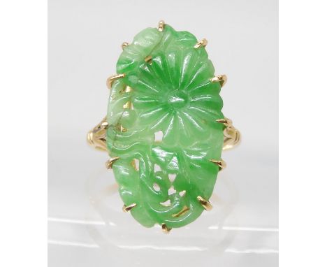 AN 18CT GOLD CHINESE GREEN HARDSTONE RING carved with a chrysanthemum and foliage, claw set to the pierced scalloped setting.