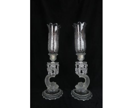 A PAIR OF BACCARAT GLASS CANDLESTICKS of frosted dolphin form, with cut glass drops and engraved glass storm shades, 58cm hig
