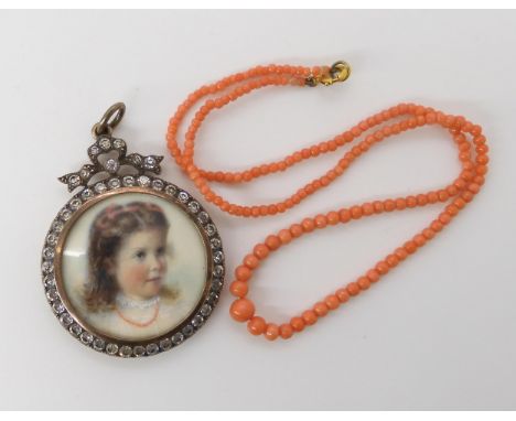 A FRENCH SILVER PORTRAIT LOCKETof a little girl in a coral necklace, in a gilded diamante set frame, diameter 3.3cm, weight 1