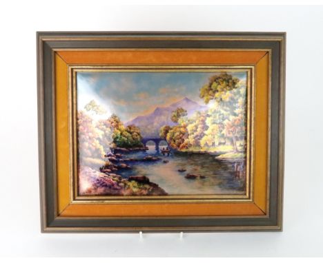 A LIMOGES ENAMEL PANEL of rectangular convex form, painted with a riverscape beside a mountain and signed L Joubert, framed, 