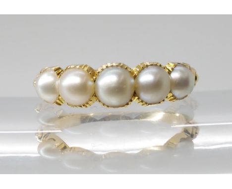 A BRIGHT YELLOW METAL PEARL RING the five half pearls are in cut back settings with reeded shoulders, largest pearl approx 5m