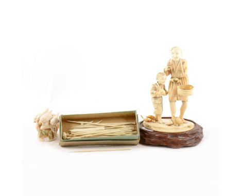 Japanese carved ivory Okimono group, Meiji period, of a merchant and boy, on wooden stand; a simulated ivory netsuke with pod