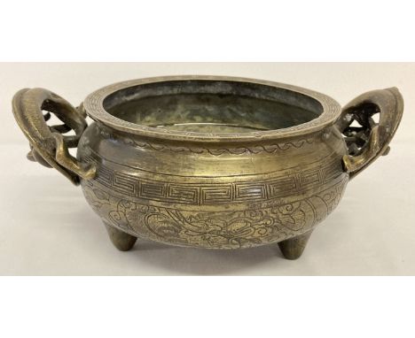 A large vintage Chinese 2 handled censer with decorative dragon shaped handles.  Raised on tripod feet with carved detail to 