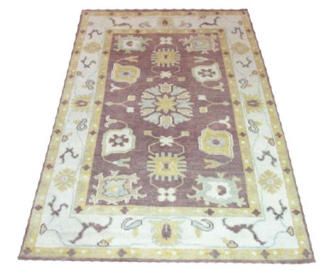 OUSHAK CARPET, 239cm x 167cm, stylised floral motifs on a contemporary amethyst field within corresponding borders. 