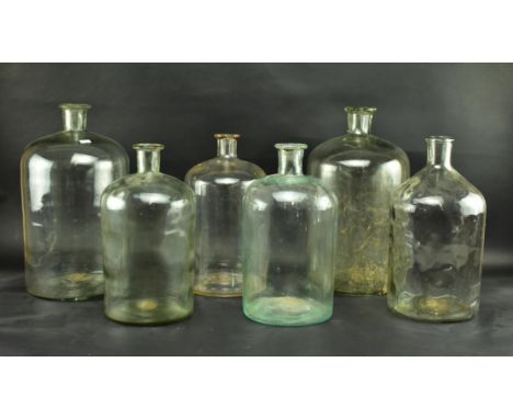 A collection of six early 20th century and later glass demijohns. The glass bottles all being of varying sizes, some appearin