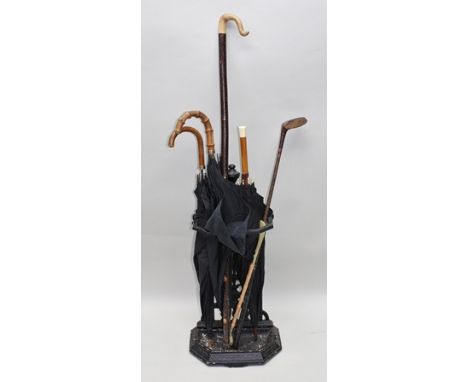 A CAST IRON STICK AND UMBRELLA STAND of aesthetic design, with removable drip tray, containing various umbrellas etc. 