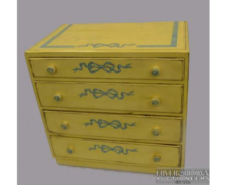 A vintage painted small chest of drawers, four long, bun handles, painted in yellow with blue bows, 75 x 76 x 46cm