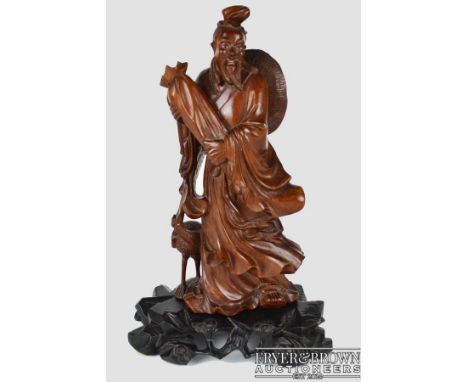 A Chinese carved wood figure of an Immortal standing holding a long scroll bag with crane to one side, inlaid glass eyes with