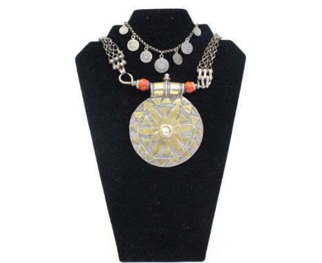 An Omani silver necklace with large flower motif, decorated disk picked out in gilding, the terminal with red ceramic beads, 