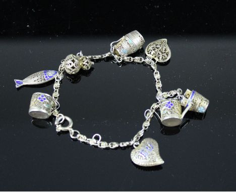 A silver gilt and enamel filigree charm bracelet includes cup, fish, heart, bucket and watering can charms, 12grs