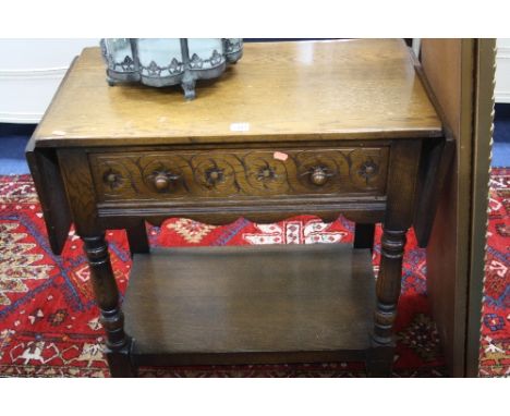 A CARVED OAK SIDE TABLE, with single drawer, drop leaf top, turned front supports and lower shelf (sd)