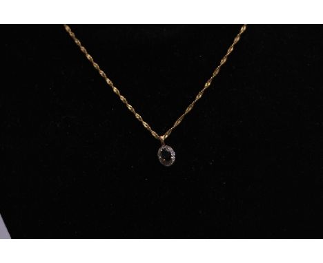 A MODERN SAPPHIRE AND DIAMOND OVAL CLUSTER PENDANT, one dark blue sapphire measuring 6 x 4mm, enclosed within a white surroun