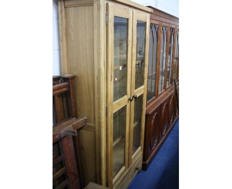 A MODERN LIGHT OAK TWO DOOR DISPLAY CABINET, with drawer below
