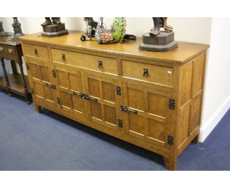 A LIGHT OAK ACORNMAN SIDEBOARD/DRESSER BASE, the central long drawer flanked by two small drawers above four panelled doors, 