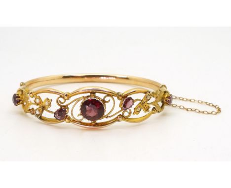 A VINTAGE FLORAL BANGLE &nbsp;set with round and pear shaped garnets and split pearls. Central garnet approx 8mm, stamped 9ct