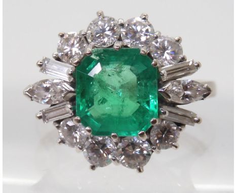 AN EMERALD &amp; DIAMOND CLUSTER RING set with a step cut emerald of approx 8.95mm x 8.33mm x 4.6mm in multi claw setting sur