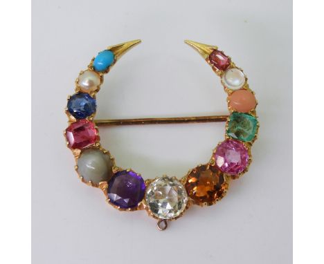 A GEM SET CRESCENT MOON BROOCH set with gem specimens to include, cats eye chrysoberyl, amethyst, sapphire, turquoise, moonst