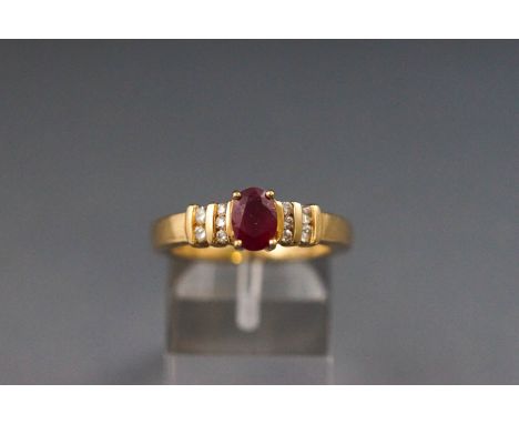 A yellow metal dress ring set with a single ruby and ten diamonds. Hallmarked 18ct gold, Birmingham. Shank stamped Iliana 18K