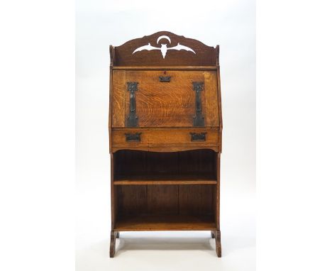 An Arts & Crafts oak bureau with cut out detail in the form of a bat and crescent moon, the fall front supported by Liberty s