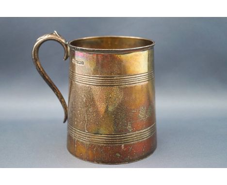 A silver half-pint mug, the straight tapering sides engraved with script initials 'AGS' and two reeded bands and with a leaf-