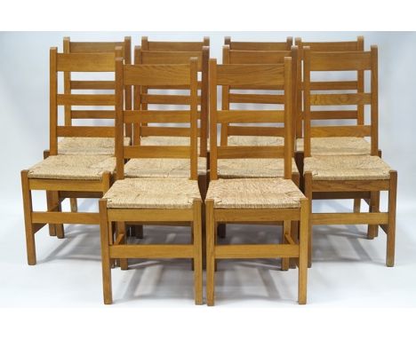 An set of ten oak ladder back dining chairs, each with drop in rush seats and square legs, linked by stretchers